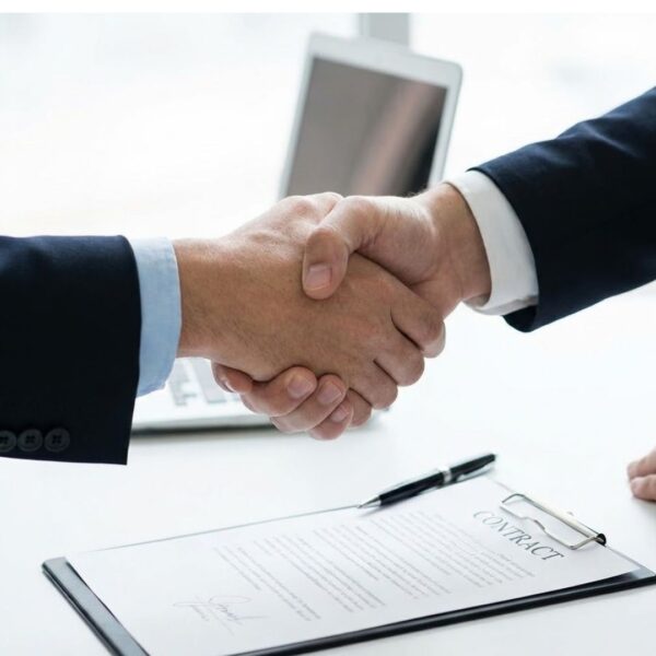 A firm handshake over a signed contract symbolizing a finalized decision.

